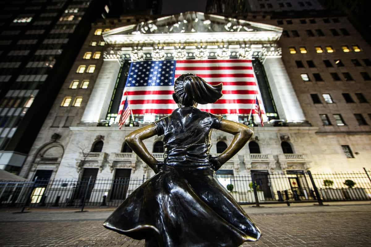 stocks to buy featuring a woman in front a building on wall street