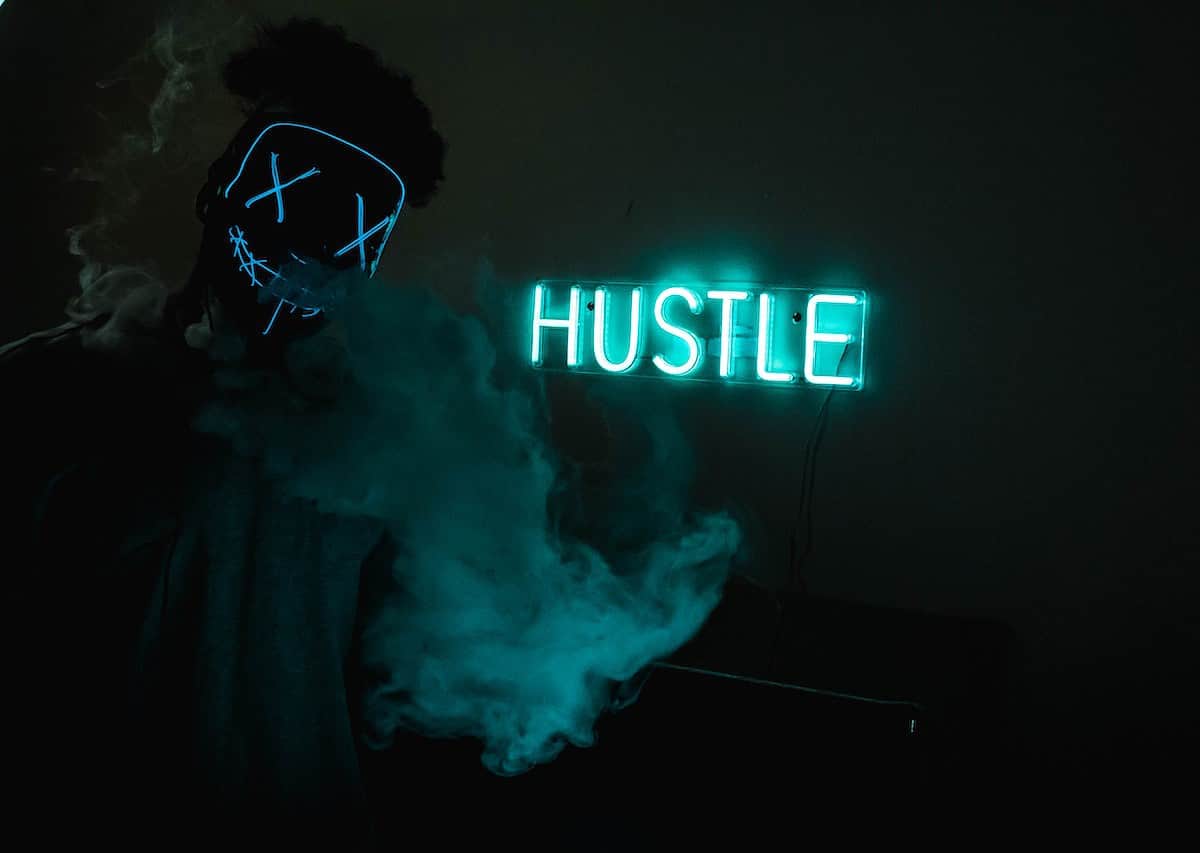 Hustle Led Signage behind person in a mask